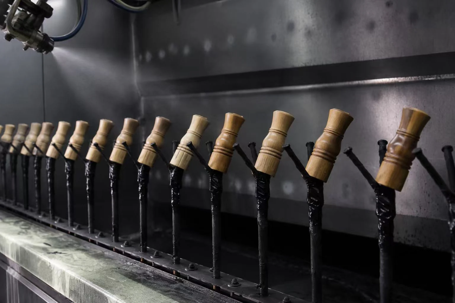 Wooden pepper mill bodies on a spray-finishing line